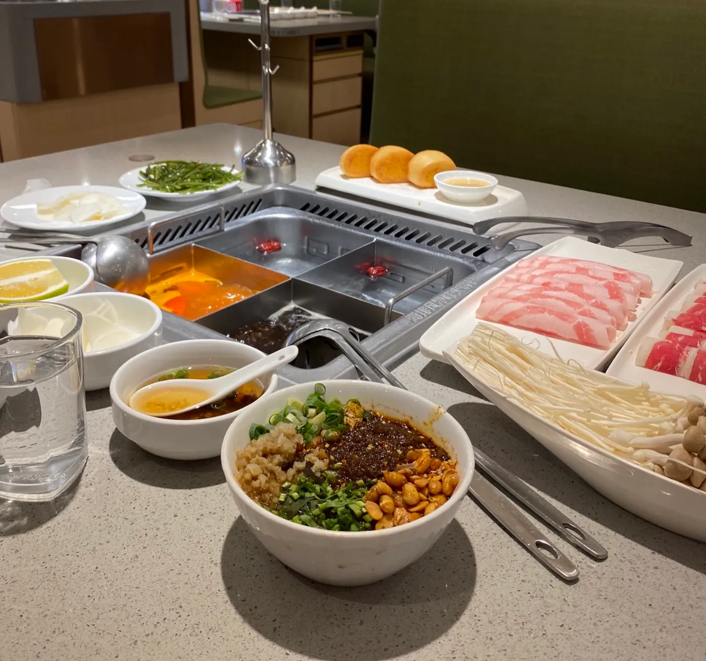 A Haidilao hotpot table with a split broth pot and dipping sauces