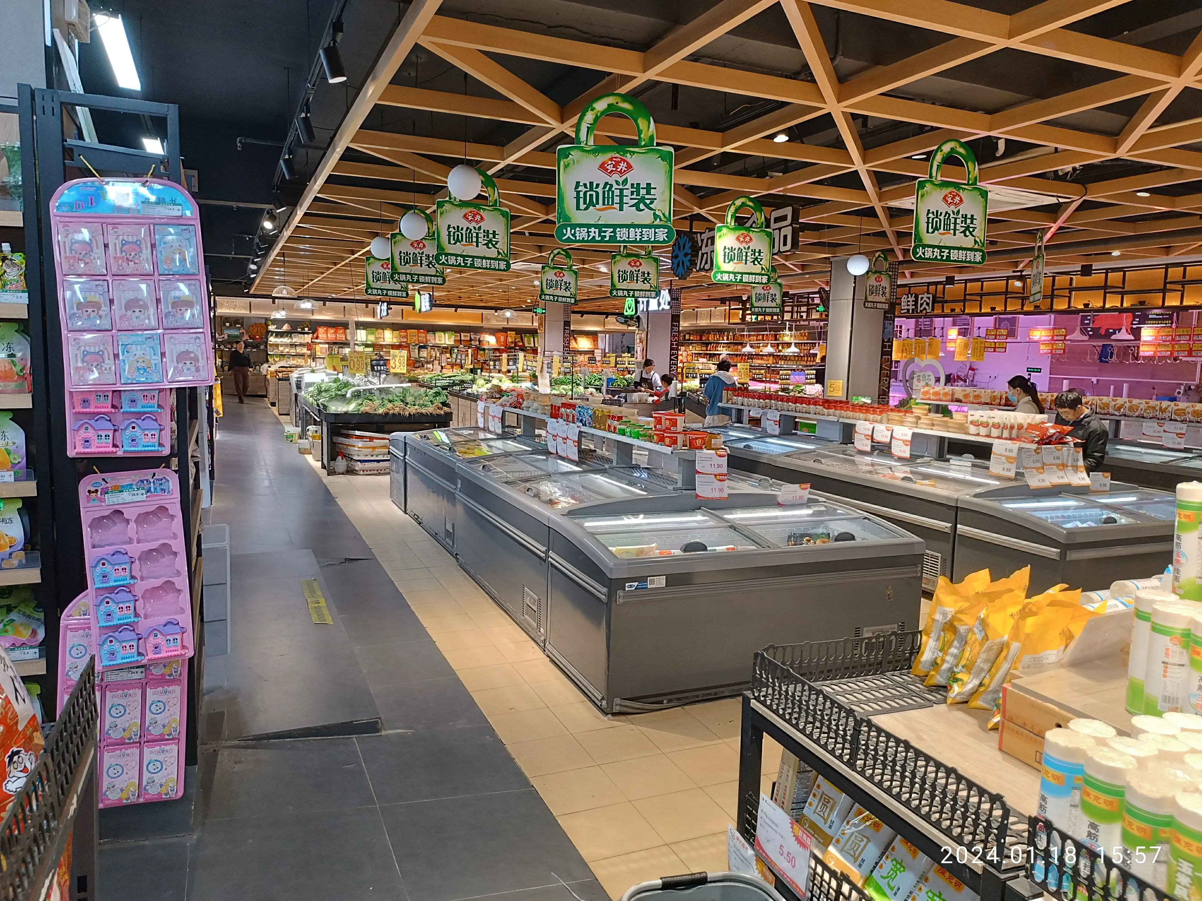 Interior of a modern Chinese supermarket with fresh produce, freezer chests and snack aisles