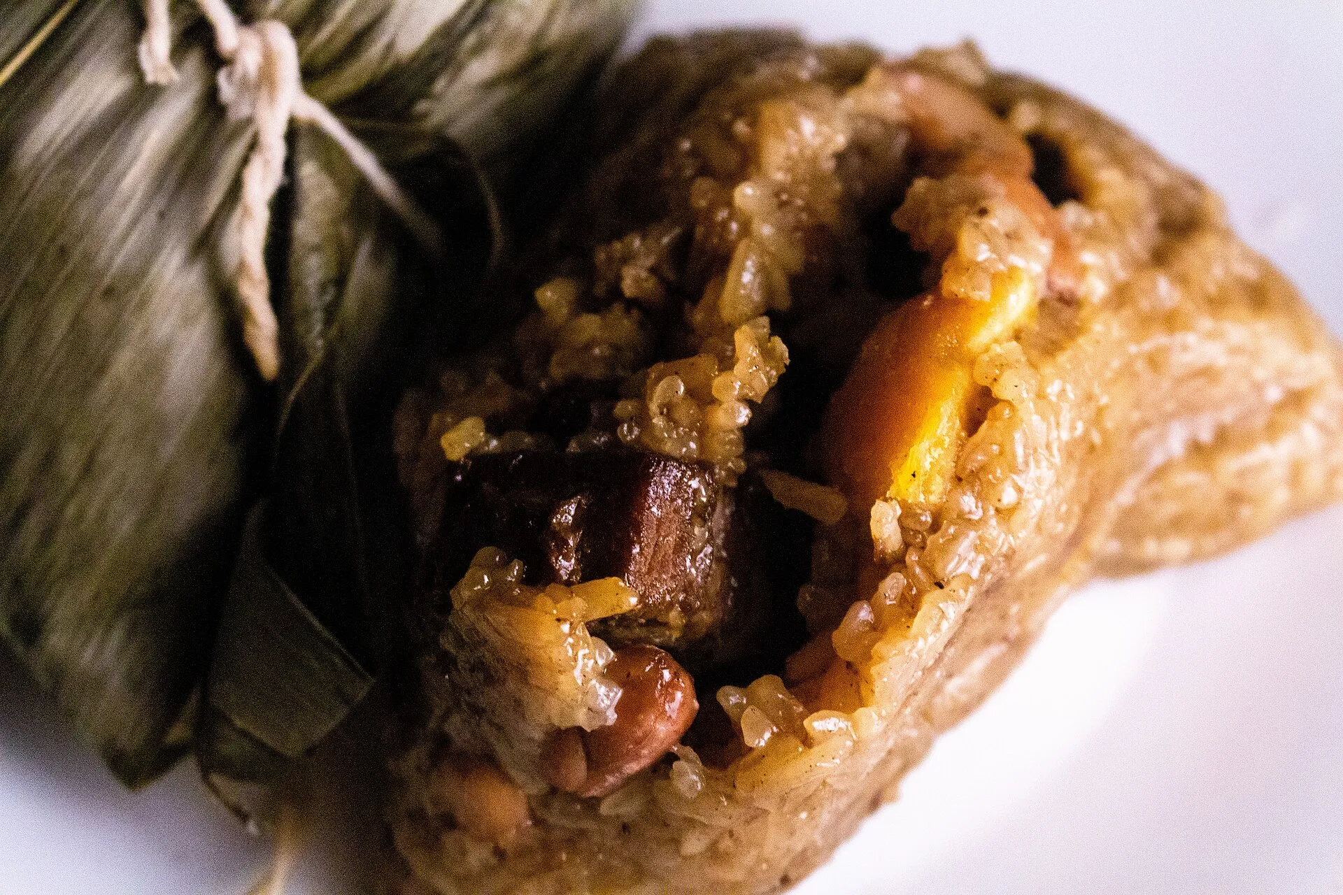開いた塩味の粽（もち米・豚肉・塩漬け卵黄）と、包まれたままの粽