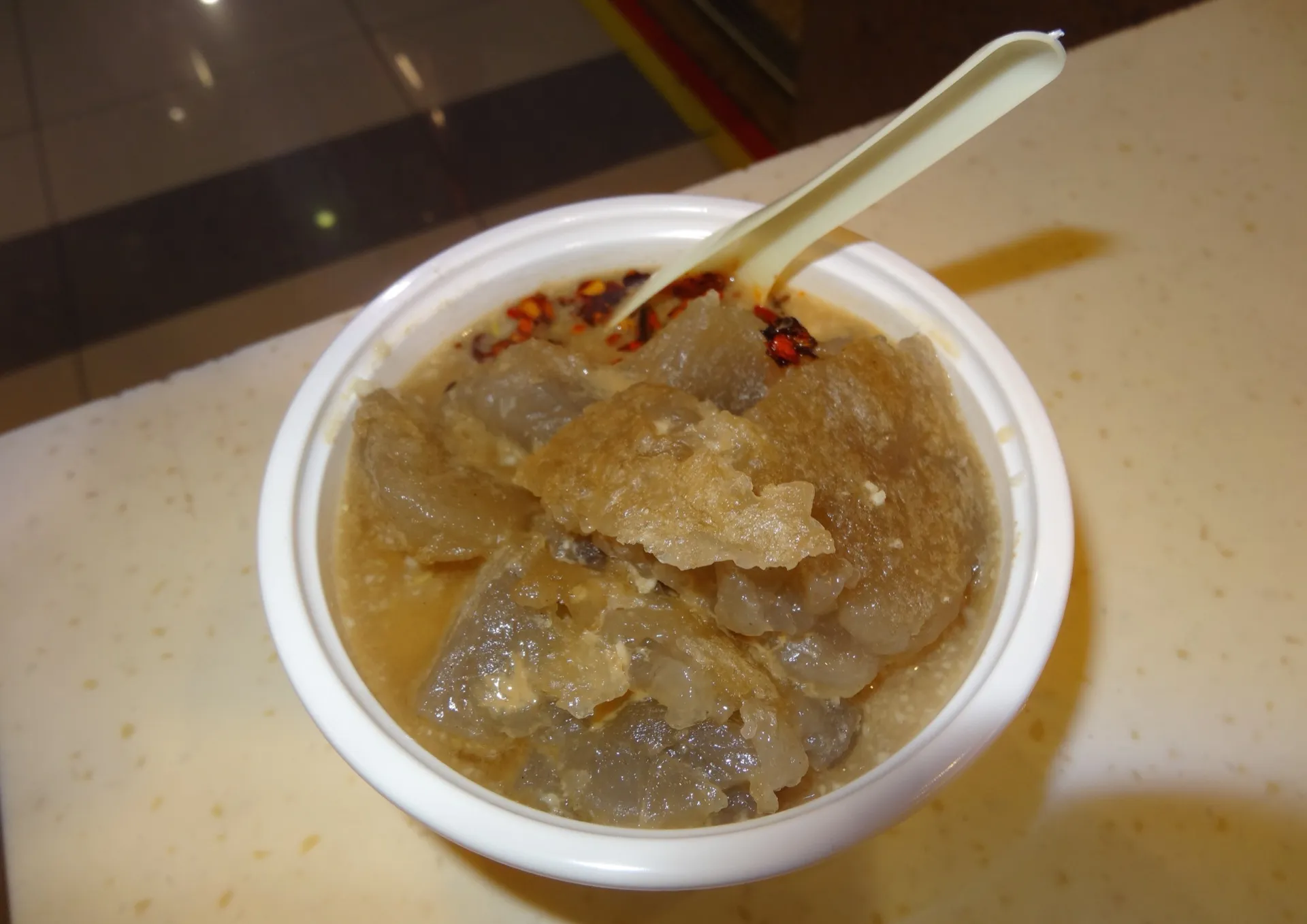 A bowl of Dalian menzi — wobbly starch-jelly cubes in a sesame-and-garlic sauce flecked with chilli
