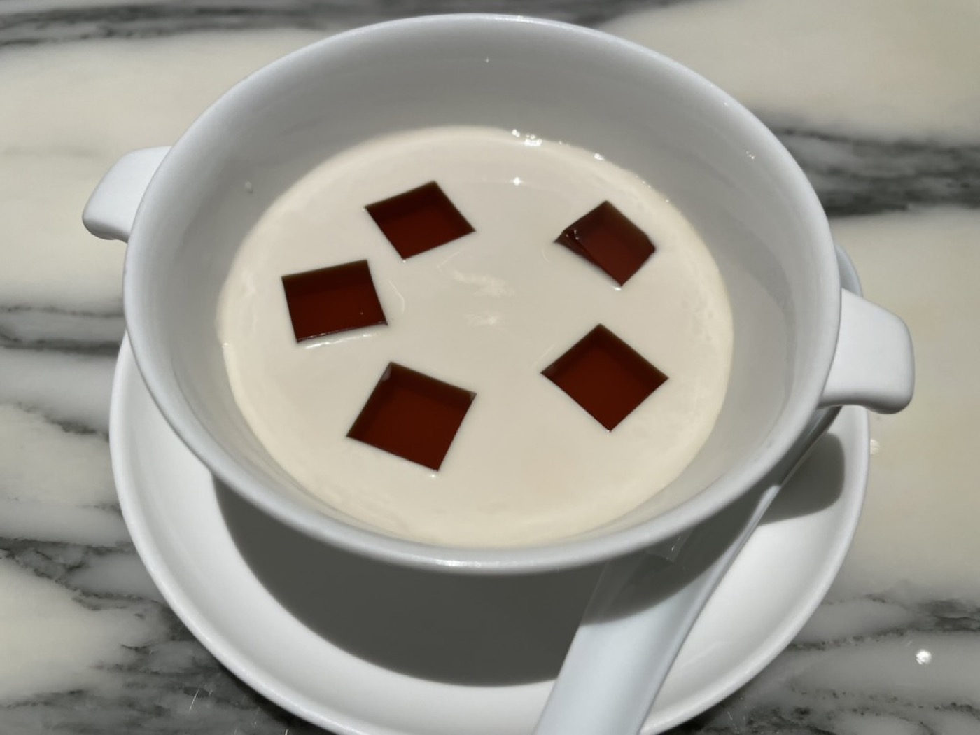 ひし形にカットした大紅袍茶ゼリーをのせた、なめらかな冷製ミルクプリン